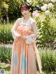 A woman in a pink and blue hanbok standing in a garden.