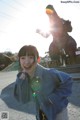 A young girl standing in front of a statue of a dinosaur.