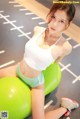 A woman sitting on a green ball in a gym.