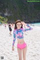 A woman in a pink bikini standing on a beach.