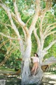 A woman leaning against a tree in a park.