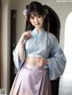 A woman in a blue and purple hanbok posing for a picture.