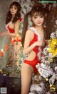 A woman in a red lingerie standing next to a Christmas tree.