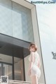 A woman in a white dress standing in front of a Louis Vuitton store.