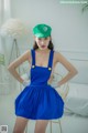 A woman in a blue dress and a green hat.