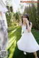 A woman in a white dress standing in the grass.