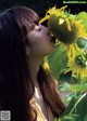 A woman is kissing a sunflower in a field.