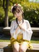 A woman in a yellow skirt sitting on a wooden bench.