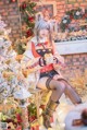 A woman sitting on a chair in front of a Christmas tree.