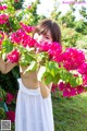 A woman in a white dress holding a bunch of pink flowers.